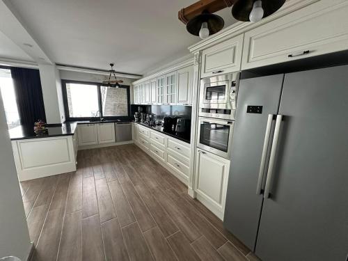 a kitchen with white cabinets and a stainless steel refrigerator at Villa Paradise in Milas