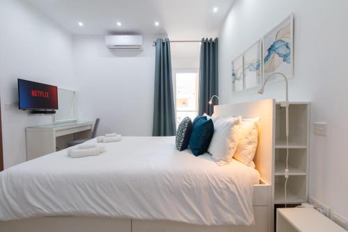 a bedroom with a large bed with a tv on it at Sandstone Apartment 17 in Marsaskala