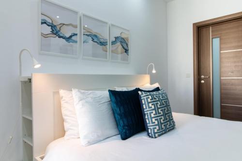 a bedroom with a white bed with blue and white pillows at Sandstone Apartment 17 in Marsaskala