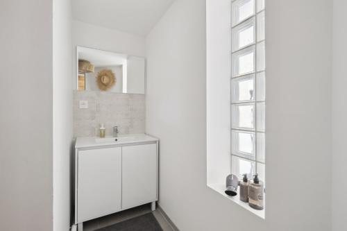 une salle de bain blanche avec un lavabo et une fenêtre dans l'établissement A Rooftop in Paris, à Paris