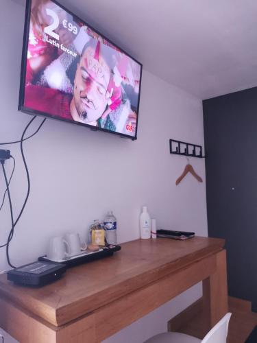 une télévision à écran plat suspendue au-dessus d'une table en bois. dans l'établissement Cazama-Chambre indépendante, à Bouchemaine