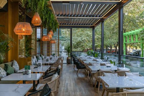 a restaurant with tables and chairs and large windows at Novos Luxury Suites in Bucharest