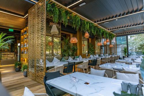 a restaurant with white tables and chairs and plants at Novos Luxury Suites in Bucharest