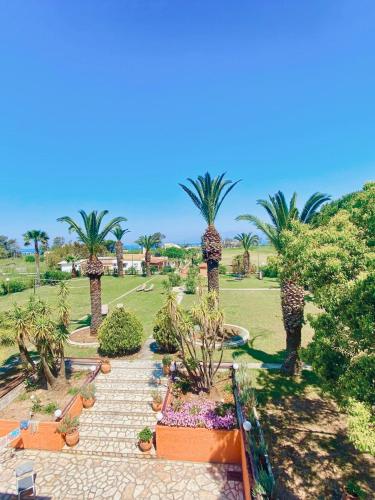 a garden with palm trees and a pathway at Villa Pami in Almiros Beach