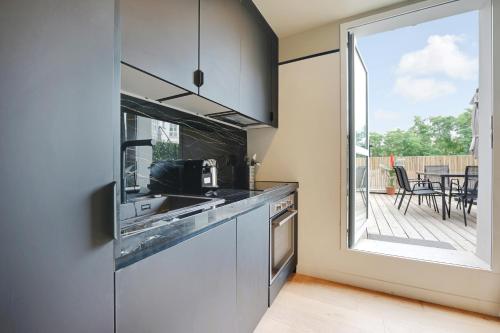 Il comprend une cuisine avec un évier et offre une vue sur une terrasse. dans l'établissement La Maison Bizot 41 T1 by ecoflats, à Paris