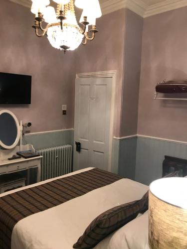 a bedroom with a bed and a chandelier at Blair Villa South in Oban