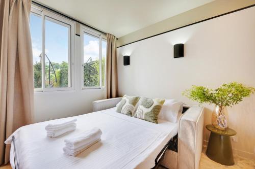une chambre avec un lit blanc avec une fenêtre dans l'établissement La Maison Bizot 41 T1 by ecoflats, à Paris