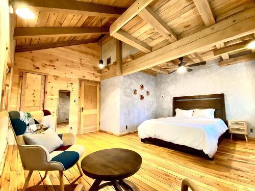 a bedroom with a bed and a table and a chair at The Arete Hostel and Suites in Summersville