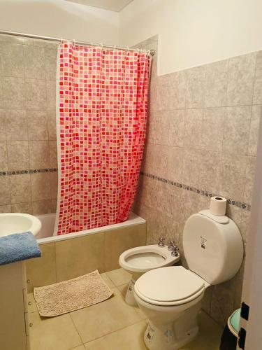 un bagno con un water e una tenda da doccia rossa di Alquileres Buendia 2 a Puerto Madryn