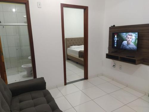 a living room with a television and a mirror at Apartmento 304 Charmoso no Centro de Conquista in Vitória da Conquista