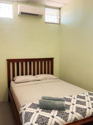 a bedroom with a bed with a blanket and two windows at D's Inn in San Ignacio