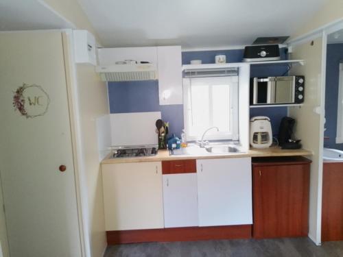 une petite cuisine avec des armoires blanches et un évier dans l'établissement ROEVMi, à Gère-Belesten