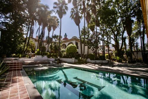 a swimming pool in front of a house with palm trees at Hotel Hacienda San Isidro in San Isidro Mazatepec