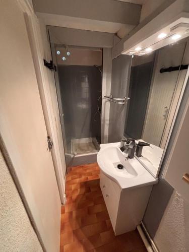 une salle de bain blanche avec un lavabo et une douche dans l'établissement Appartement proche Lydia à deux pas des déferlantes et de la grande plage, au Barcarès