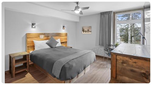Un dormitorio con una cama y un escritorio y una ventana. en Hôtel Far Hills, en Val-Morin