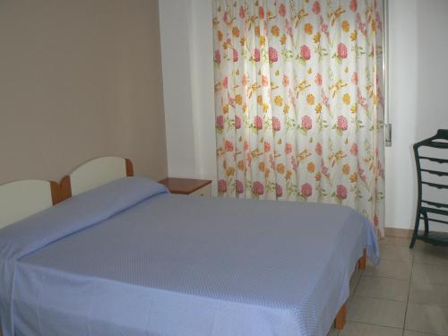 a bedroom with a blue bed and a curtain at Central Palace Malfà in Scoglitti