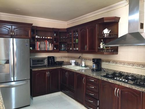 a kitchen with wooden cabinets and a stainless steel refrigerator at Casa Belén, Amplia, con Garaje y zona de trabajo in Roldanillo