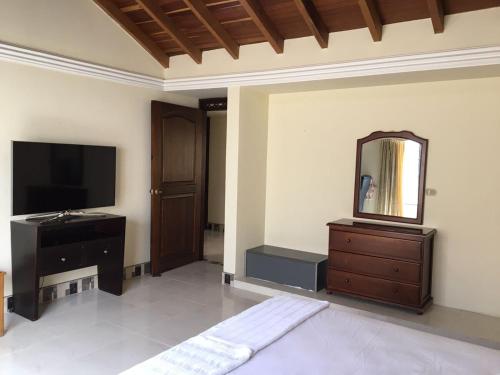 a living room with a television and a mirror at Casa Belén, Amplia, con Garaje y zona de trabajo in Roldanillo