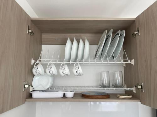 a kitchen with white plates and utensils on a shelf at Muy Cerca al CC Fundadores, U Autonoma & El Centro in Manizales