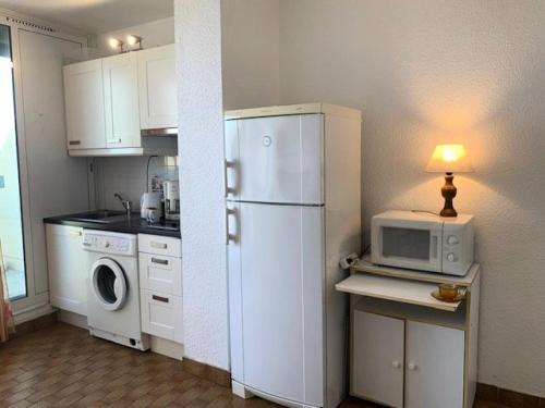 La cuisine est équipée d'un réfrigérateur blanc et d'un four micro-ondes. dans l'établissement Résidence Héliopolis Bâtiment Ab - Studio 4 pers Héliopolis Bât AB très grande terrasse MAE-2984, au Cap d'Agde