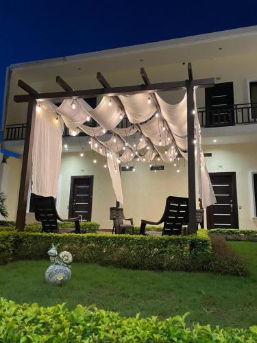 a pavilion with curtains and lights in front of a house at Hotel Margarita in Flores