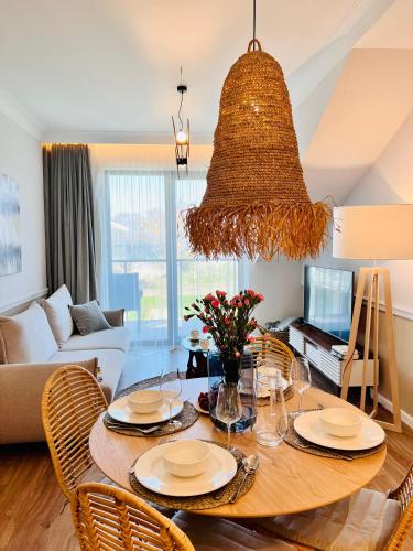 a living room with a table with chairs and a large chandelier at Rezydencja Niechorze MORSKIE WIDOKI 313 z Basenem i SPA - 5D Apartments in Niechorze