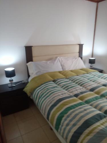 a bed with a striped comforter in a bedroom at Cabaña la Morocha in Ciudad Lujan de Cuyo