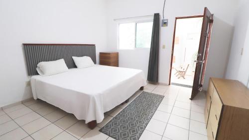 a bedroom with a large white bed and a window at Mezcales Inn in Mezcales