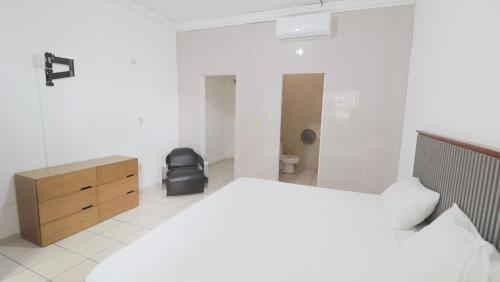 a white bedroom with a bed and a dresser and a chair at Mezcales Inn in Mezcales