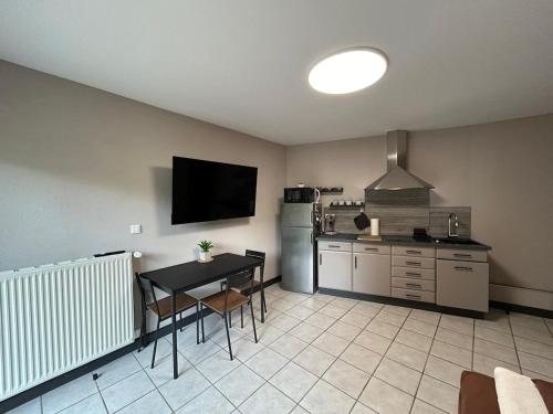 une cuisine avec une table, une télévision, une table et des chaises dans l'établissement T2 Chaleureux logement a Thann, à Thann