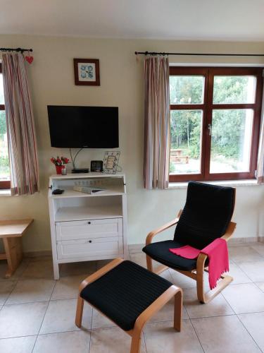 a living room with a chair and a desk with a television at Wellness Chata Rosnatka in Kvilda