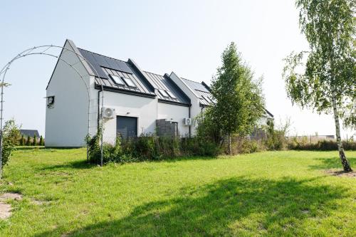 a white house with a large yard in front of it at Domki Ostoja - nad Bałtykiem - cisza i piękno natury in Zastań