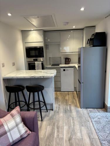 a kitchen with a refrigerator and two bar stools at Loom Lodge in Great Wyrley