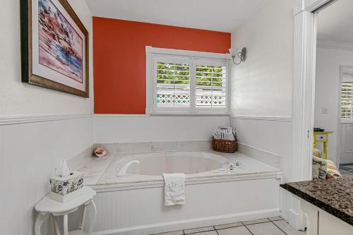 a white bathroom with a tub and a window at Windemere Inn by the Sea in Melbourne