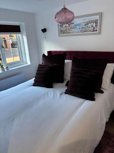 a large white bed with black pillows in a bedroom at Loom Lodge in Great Wyrley