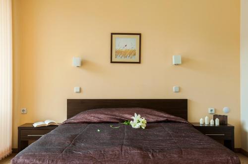 a bedroom with a bed with a flower on it at Хотел Дикас in Smolyan