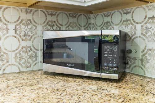 a microwave sitting on a counter in a kitchen at New Year Spot- Navy Graduation King bed pool table in Beach Park