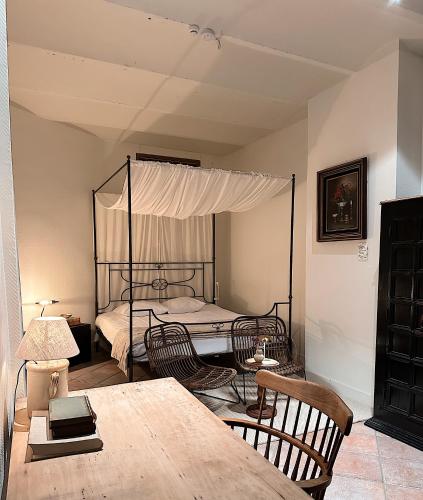 a bedroom with a canopy bed with chairs and a table at Gent Gently apartment in center in Ghent