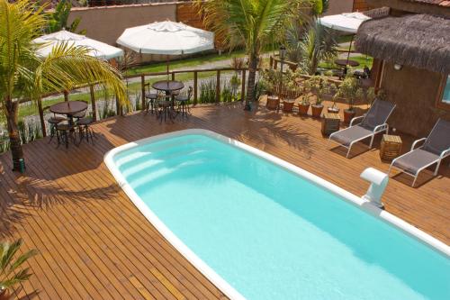 uma piscina num deque com cadeiras e mesas em Pousada de Charme Emirados em Ilhabela