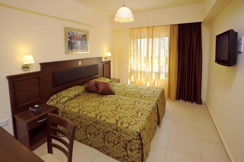 a bedroom with a bed and a table and a television at Euronapa Hotel Apartments in Ayia Napa