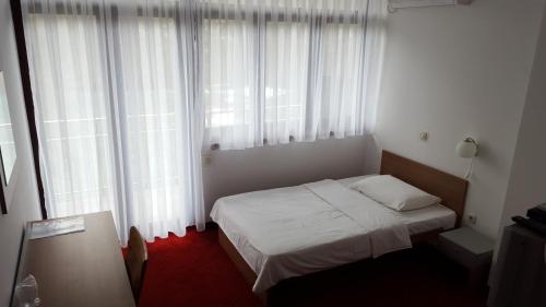 a bedroom with a bed and a window with white curtains at Bed & Breakfast Zeleni Kut in Gornji Zvečaj