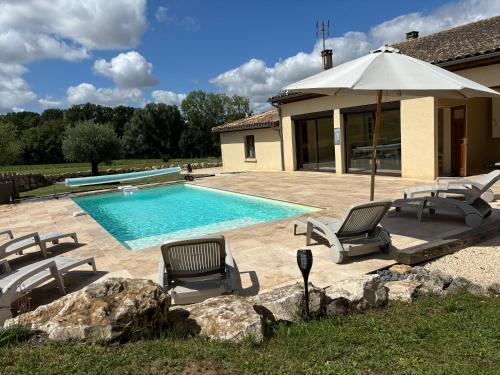 une piscine avec des chaises et un parasol dans l'établissement Maison de charme avec piscine chauffée, à Nojals-et-Clottes