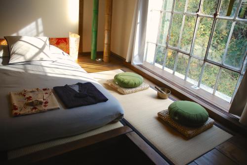 a bed with two green pillows on the floor next to a window at Minshuku Chambres d'hôtes japonaises in Thiers
