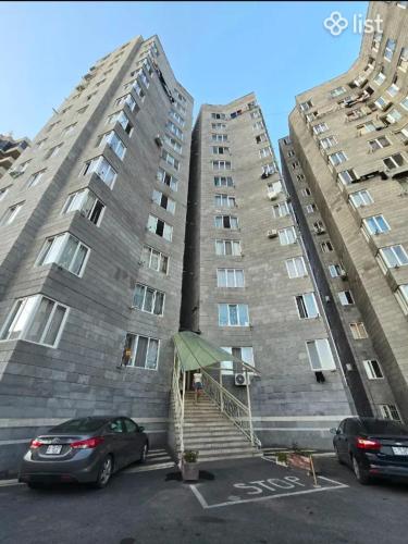 zwei hohe Gebäude mit Autos auf einem Parkplatz in der Unterkunft Modern 2-Room Comfort Apartment in Yerevan, Norashen in Yerevan