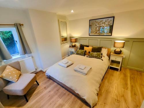 ein Schlafzimmer mit einem großen Bett und einem Stuhl in der Unterkunft Trillis Cottage in Sapperton