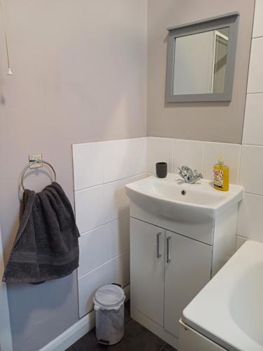 a white bathroom with a sink and a mirror at Home from Home in Faversham