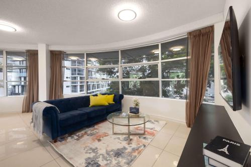 a living room with a blue couch and a large window at Newly Renovated 3BR Apartment 2 Parking Spaces Pool Gym City Views Walk to Shops in Brisbane