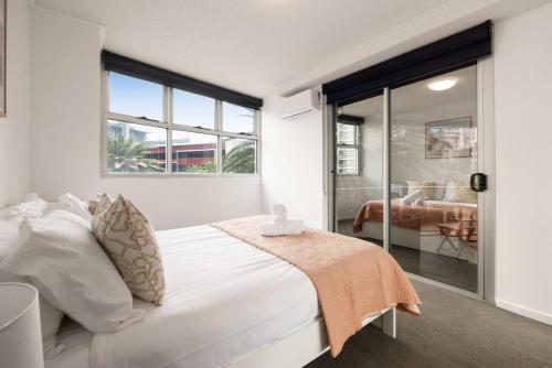 a white bedroom with a bed and a sliding glass door at Newly Renovated 3BR Apartment 2 Parking Spaces Pool Gym City Views Walk to Shops in Brisbane