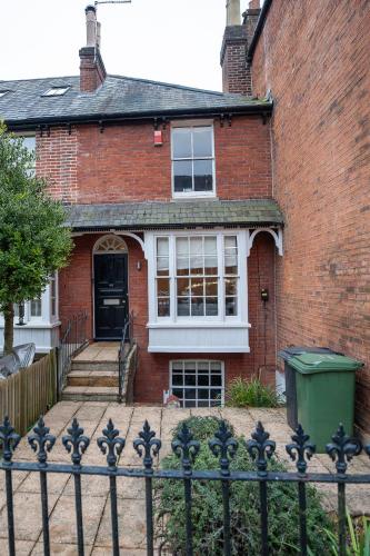 a brick house with a fence in front of it at 4 Bedroom Winchester Town House, central, parking in Winchester