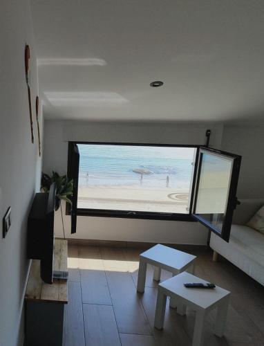 a living room with a large window of a beach at Burela Mariña Playa in Burela de Cabo